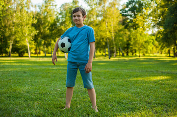 Photo of a kid smiling at the camera and holding a soccer ball