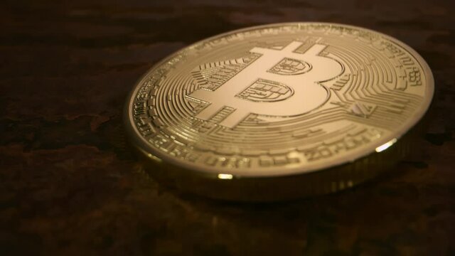 Close up super slow motion shot of a single bitcoin falling onto a rust surface
