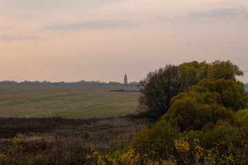 Top view on country landscape with tower, field, trees in sunny autumn evening