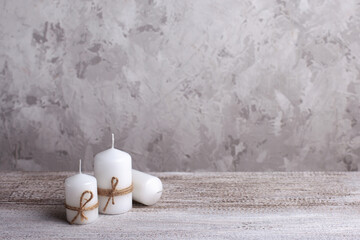 mock up of three white candles in a jute rope on a wooden table.