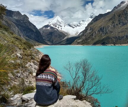 Girl at Laguna Paron, Huaraz, Peru. A blue-green lake in the Cordillera Blanca on the Peruvian Andes. At 4185 meters above sea level, it's surrounded by snowy peaks and a pyramid mountain. 