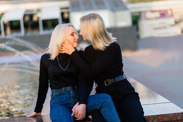 Two young females walking smiling embracing and kissing outdoor in the city