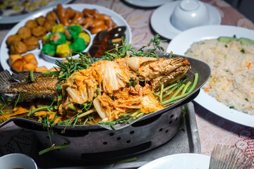 Snakehead with dressing.  Steamed whole fish with sauce. Steamed whole fish with sauce and with dressing with water mimosa on wood table.