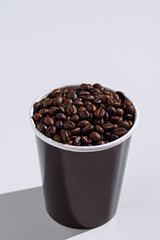 close-up of disposable paper Cup with coffee beans on white background, copy space, mockup