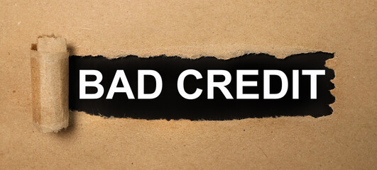 The text bad credit appearing behind torn brown paper