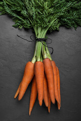 Bunch of tasty raw carrots on black slate table, top view