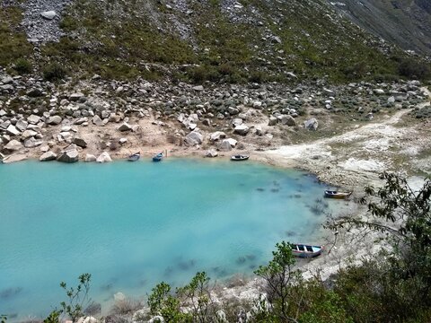Boats at Laguna Paron, Huaraz, Peru. A blue-green lake in the Cordillera Blanca on the Peruvian Andes. At 4185 meters above sea level, it's surrounded by snowy peaks and a pyramid mountain. 