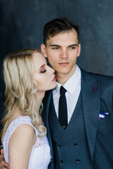 Cute wedding couple in interior of classic studio. They kiss and hug each other.