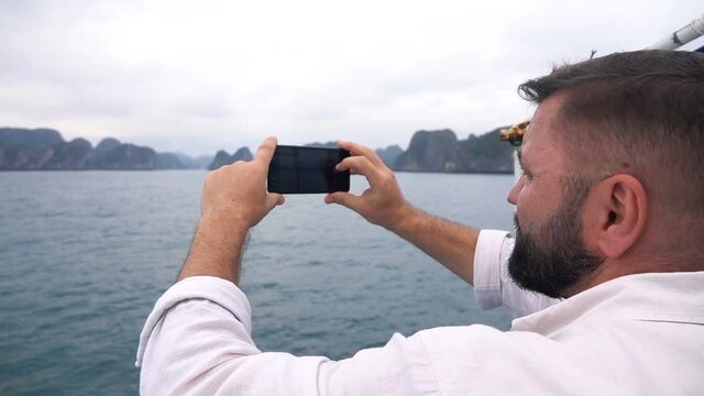 Young man taking photos during cruise at Ha Long bay, slow motion