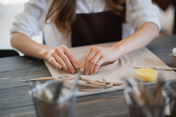 Artisan female potter prepares material for her pottery. Woman hands attach clay part to future ceramic product. Work close-up.