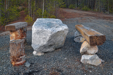 Homemade picnic table made of stones and logs in the forest.