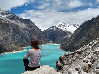 Fototapeta na wymiar Girl at Laguna Paron, Huaraz, Peru. A blue-green lake in the Cordillera Blanca on the Peruvian Andes. At 4185 meters above sea level, it's surrounded by snowy peaks and a pyramid mountain. 