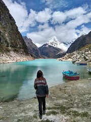 Girl at Laguna Paron, Huaraz, Peru. A blue-green lake in the Cordillera Blanca on the Peruvian Andes. At 4185 meters above sea level, it's surrounded by snowy peaks and a pyramid mountain. 