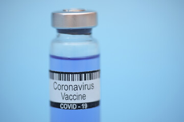 Coronavirus vaccine in bottle on blue background with space for text. Victory over Corona virus SARS-CoV-2 epidemic, scientists have found vaccine against coronavirus SARS-COV2.