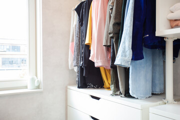 Colorful collection of women's clothes hanging on a rack, modern casual closet in light room , modern dressing room