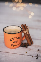 vintage orange coffee cup with cinnamon and star anise on a white wooden background. christmas spices. Vintage tones with bokeh light