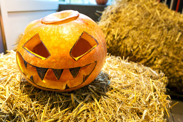 A pumpkin on a straw with an angry expression on Halloween.