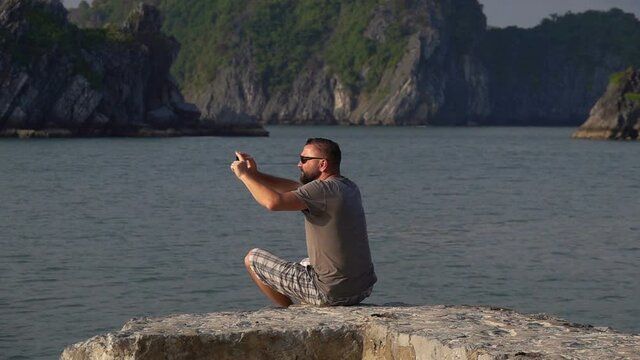 Young man taking photos of amazing Ha Long bay, slow motion