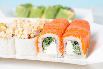 Food delivery, takeaway concept. Lunch box with sushi set. Assorted sushi, Philadelphia roll, cheese, with squid on white light background. Copy space. Tasty vegetarian lunch, Japanese cuisine seafood