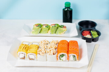 Food delivery, takeaway concept. Lunch box with sushi set. Assorted sushi, Philadelphia roll, cheese, with squid on white light background. Copy space. Tasty vegetarian lunch, Japanese cuisine seafood