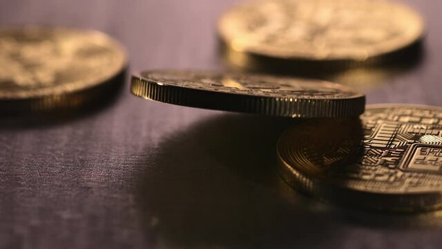 Slow motion shot of bitcoins falling onto a steel surface. 