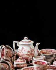 Closeup view of colorful ceramic vintage tea set standing on a tray on black background. space for text