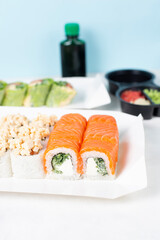Food delivery, takeaway concept. Lunch box with sushi set. Assorted sushi, Philadelphia roll, cheese, with squid on white light background. Copy space. Tasty vegetarian lunch, Japanese cuisine seafood