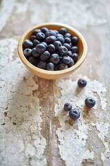Image of blueberries in wooden bowl on rustic village table.