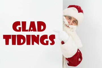 Santa Claus points his fingers at the board with the text - GLAD TIDINGS