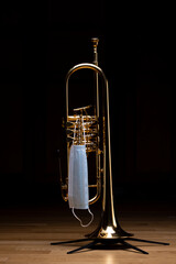 A gold plated rotary trumpet with a medical mask on, to represent restrictions on concerts and...