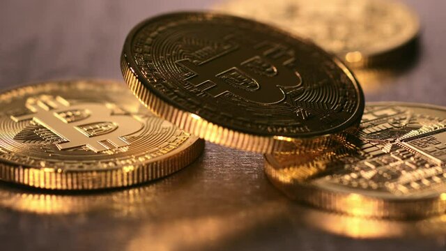 Slow motion shot of bitcoins falling onto a steel surface.