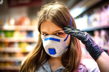 Girl wears protected mask in store. Shopping time during coronavirus outbreak. Girl in a medical mask. Quarantine and protection virus, flu, epidemic COVID-19. Coronavirus quarantine.