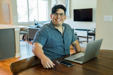 Portrait of smiling man working from home at dining room table