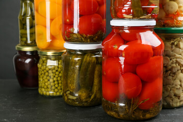 Jars of pickled vegetables on grey table, closeup