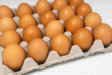 Brown fresh chicken eggs in large cardboard box.