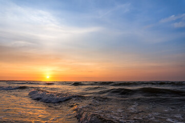 Fototapeta premium Sunset over the sea. Reflection of sunlight in the sea waves. The sky in the sunset rays. Russia Baltic Sea.
