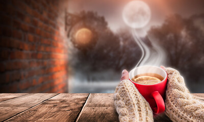 Red cup of hot tea in the interior. Cup with tea in female hands.