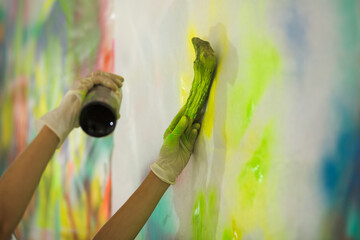 Making a painting: hands spraying color over objects