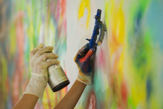 Making a painting: hands spraying color over objects