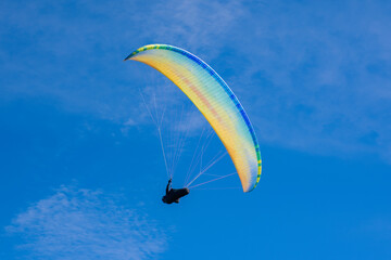 Colourful paraglider on a blue sky background. Extreme sport.
