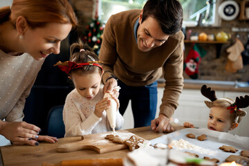 Happy family decorating gingerbread cookies on Christmas day. - Powered by Adobe