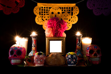 Day of the Dead offering from central Mexico with papel picado, veladoras, photography, flowers and bread of the dead