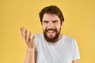 Bearded man emotions fun gesture with hands white t-shirt close-up yellow background