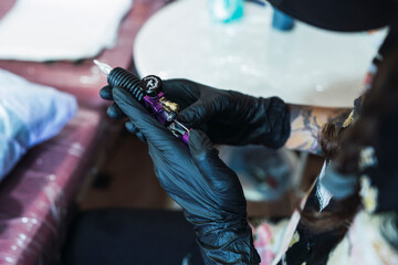 Chica joven con gafas tatuando a chico joven un dragon en el brazo