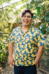 Portrait of happy, smiling latinx man in bright patterned shirt standing outside in garden