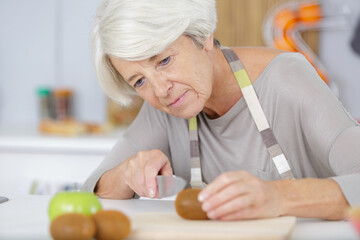 Obraz na płótnie Canvas senior woman preparing a kiwi fruit