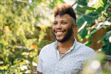 Portrait of black man with mohawk standing outdoors in garden laughing