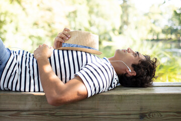 man relaxing outdoors listening to earphones