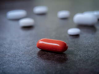 Obraz na płótnie Canvas Red capsule with white pills in background