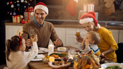 Happy family toasting during Christmas lunch at dining table.